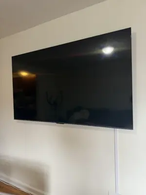 Large flat-screen TV flush-mounted on a white living room wall with clean cable management in NYC home